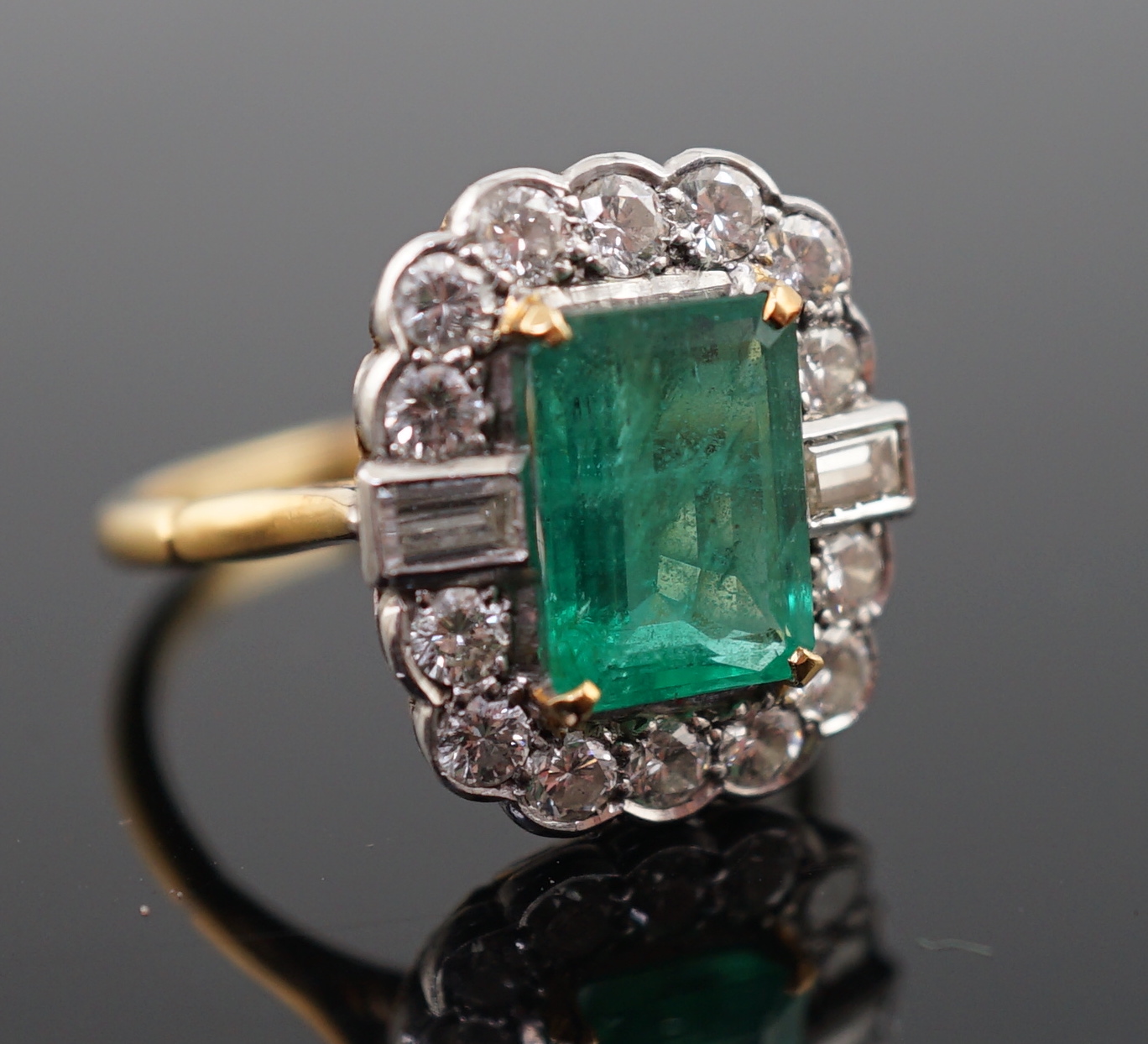 An Art Deco style yellow metal, emerald and diamond set oval cluster ring